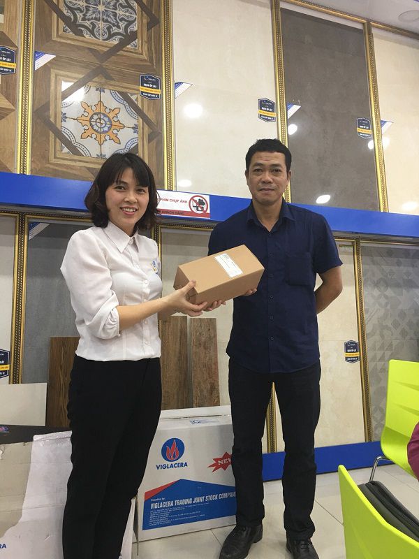 Nhân viên tư vấn đang trao món quà cho khách hàng mua tổng đơn hàng trên 30 triệu